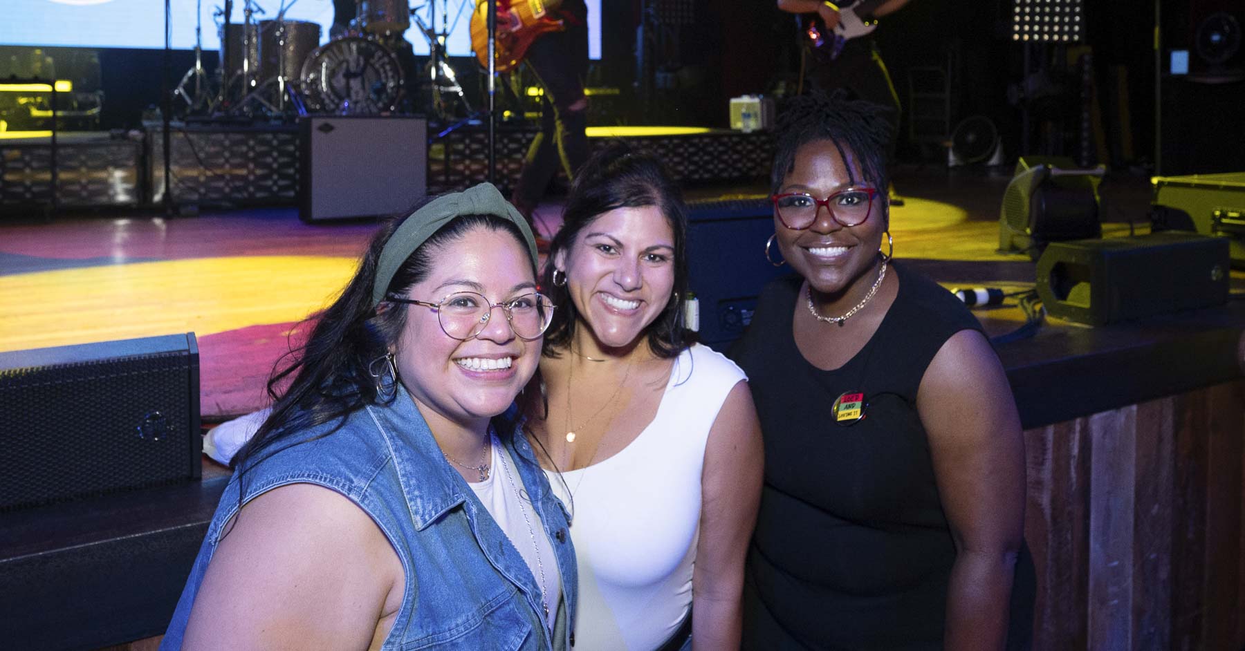 Three attendees taking a picture by the stage